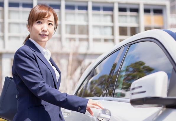 スーツ姿の女性が車のドアを開ける様子